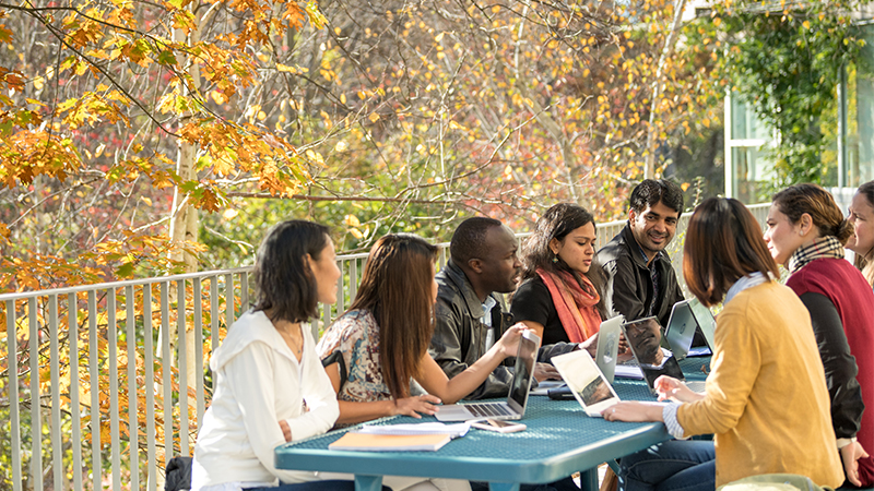 students sitting outside at picnic table in autumn