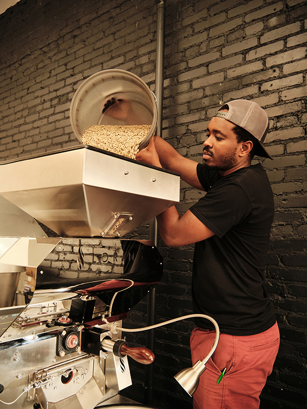 Francois Tuyishime, MA COEX'17, works with machinery at his Yego Coffee shop