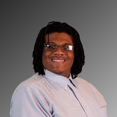 TJ Gordon, a black man with dreds and glasses is smiling at the camera, wearing a button down shirt.