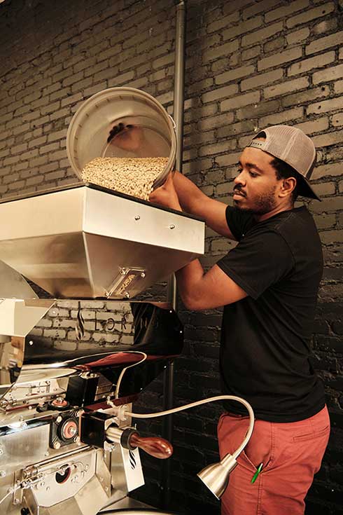 Francois Tuyishime, MA COEX'17, works with machinery at his Yego Coffee shop