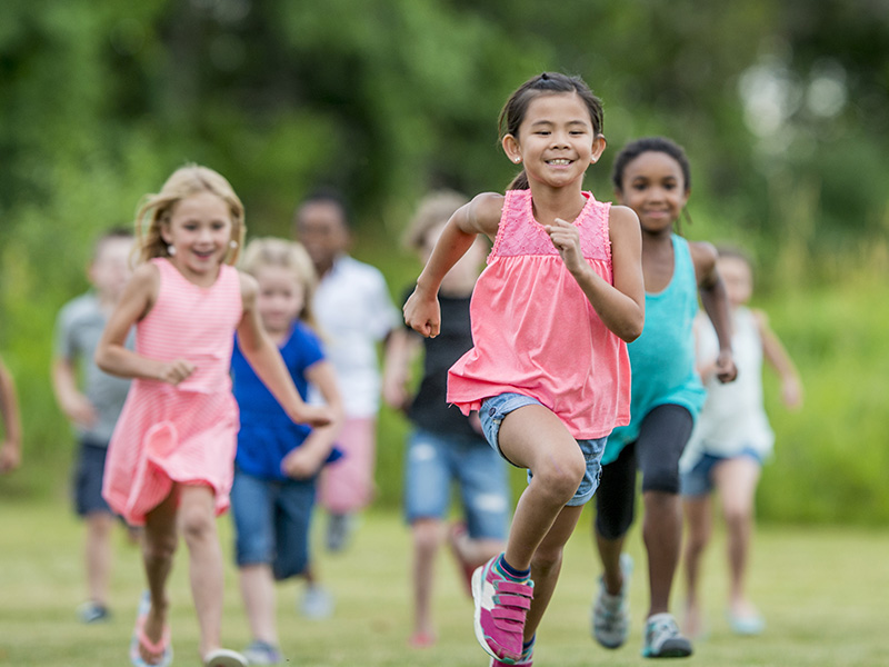 multiracial kids running in grassy field