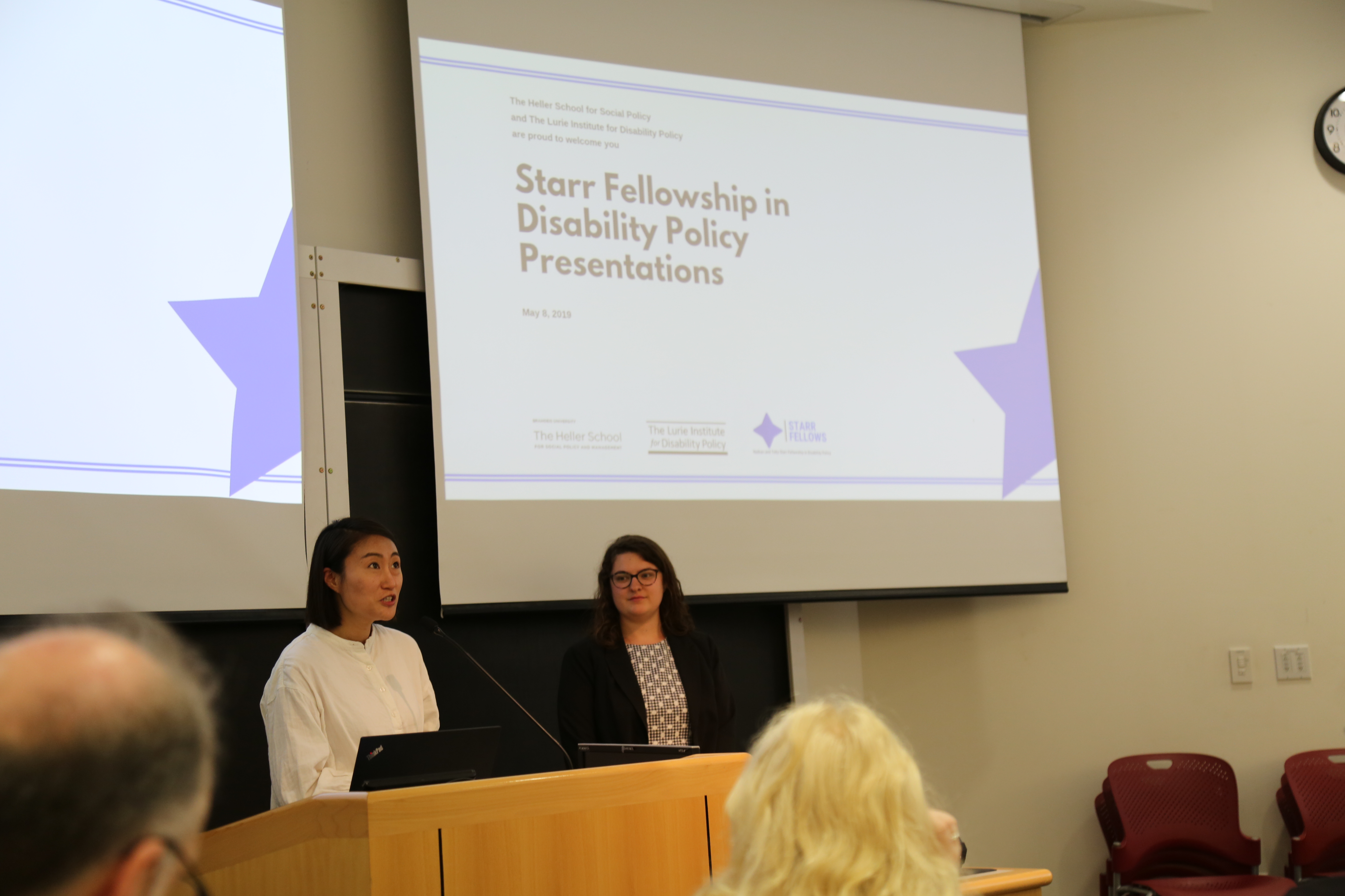 Research mentor, Eun Ha Namkung is next to research fellow, Julia Brown in a classroom behind a podium