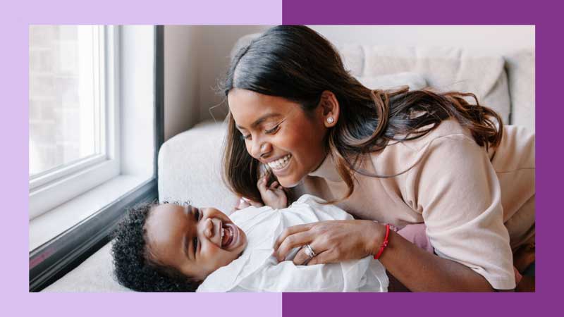 A Black mother cuddling her child. They both smile.
