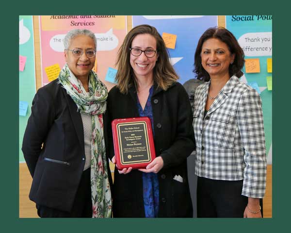 Miriam accepts award. She smiles and stands alongside Lurie Institute Director Monika Mitra and Dean Maria Madison