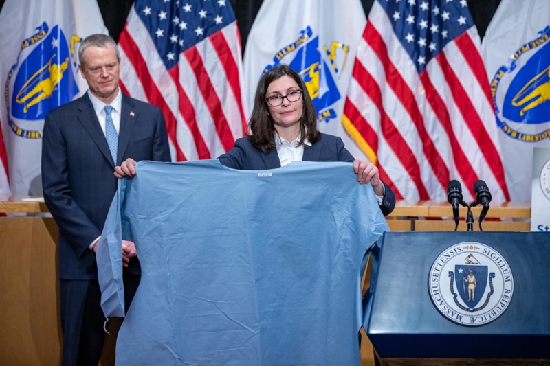 Brenna Schneider, MBA'12, displays PPE gown as Massachusetts Governor Charlie Baker looks on