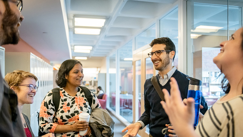 A group of students talking in a hallway of the Heller School