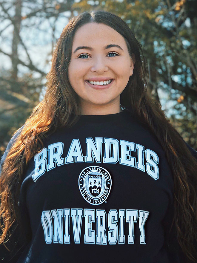 Julianna Brill, MA SID/COEX’22, in a sweatshirt that says Brandeis University with the university seal