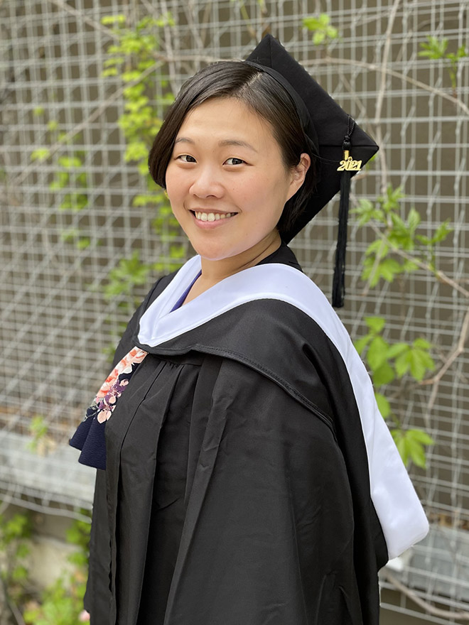 Brontte Hwang, MA SID/MBA'21, in a commencement cap and gown in front of green vines 