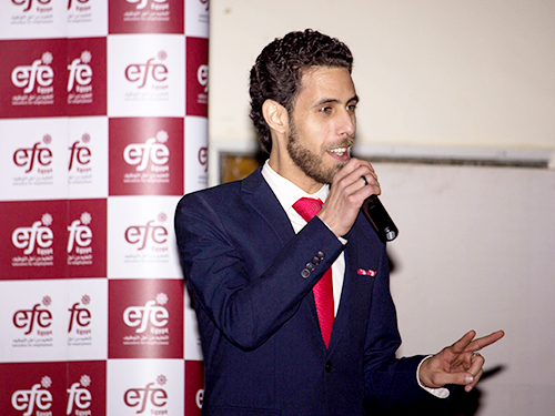 Khaled Sakr wearing a suit and speaking into a microphone in front of a corporate EFE banner