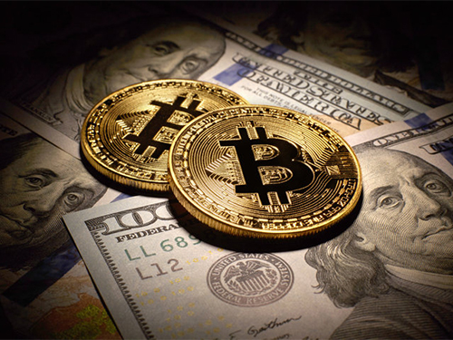 bitcoins on top of US dollar bills