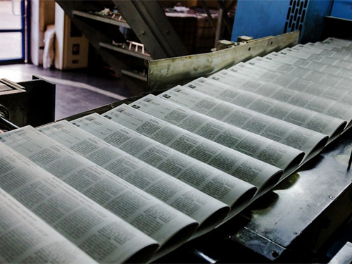newspapers moving through a printing press assembly line
