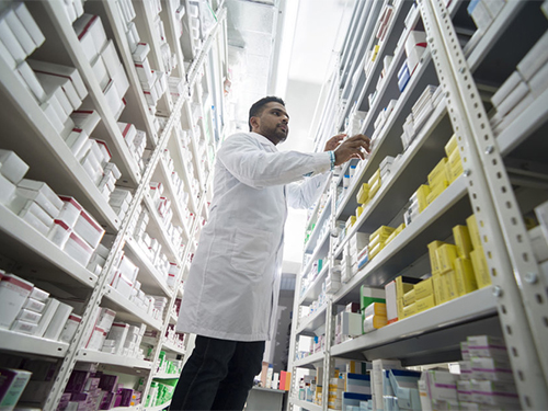 pharmacist examining shelves of prescription drugs