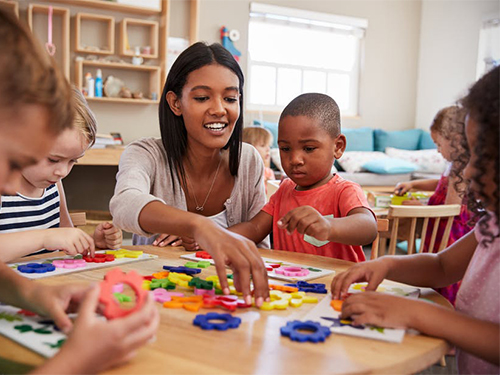 preschool teacher playing with students in classroom