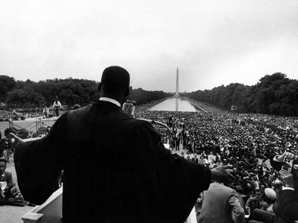 A black and white picture of Martin Luther King Jr. giving a speech to a crowd
