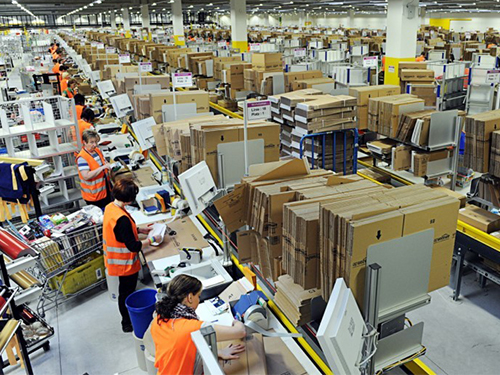an assembly line of workers packing boxes in a huge warehouse