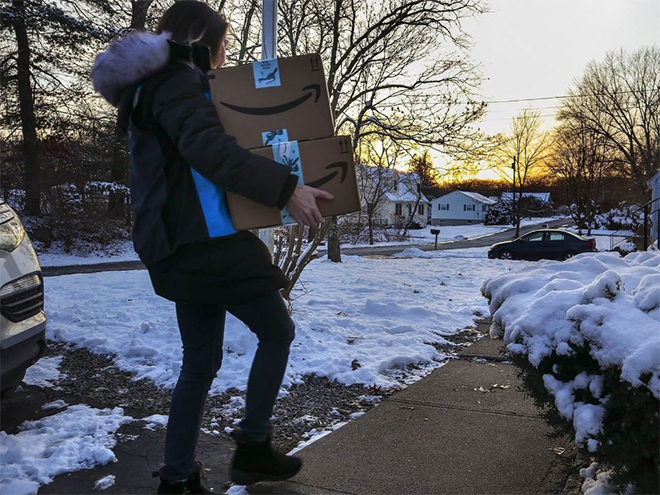 person carrying amazon boxes in snow