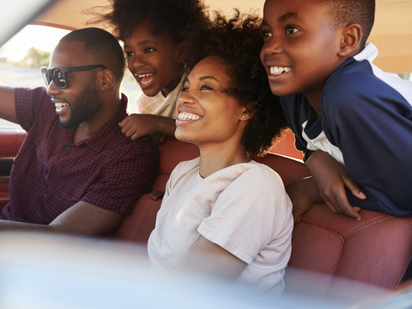 A black family with two young kids in a car