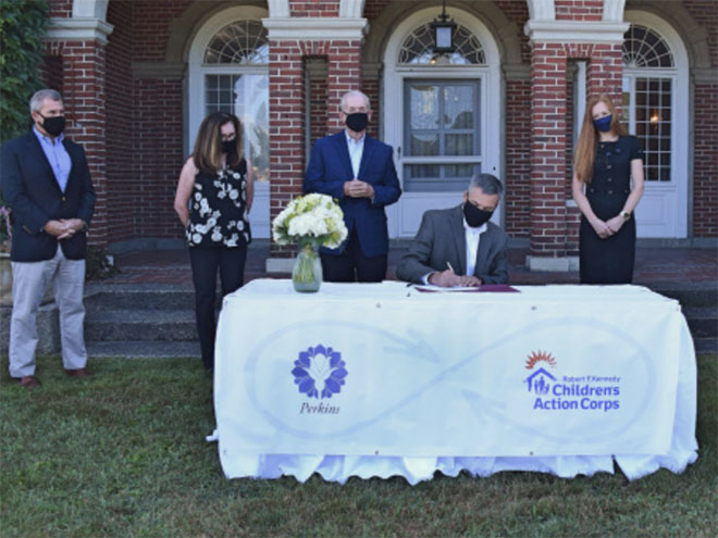 Perkins CEO Michael W. Ames signs documents officially making the Robert F. Kennedy Children's Action Corps an affiliate of Doctor Franklin Perkins School at a ceremony at Perkins in Lancaster, Massachusetts