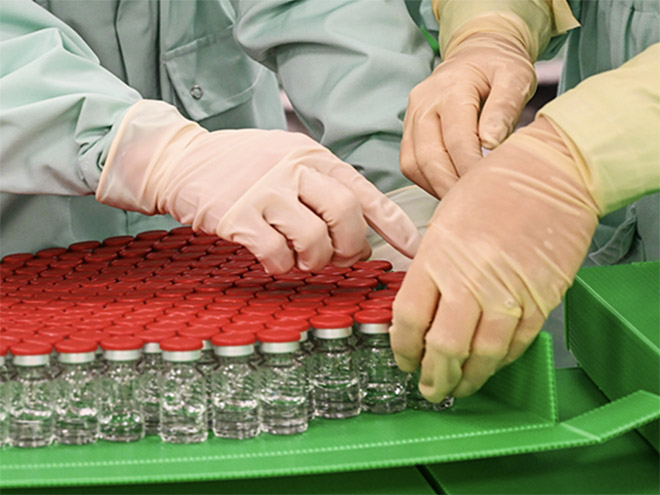 Laboratory technicians handle capped vials of the University of Oxford's COVID-19 vaccine candidate at a manufacturing facility in Italy.