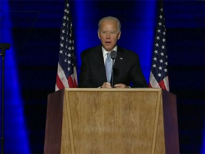 Joe Biden speaking at a podium with American flags behind him
