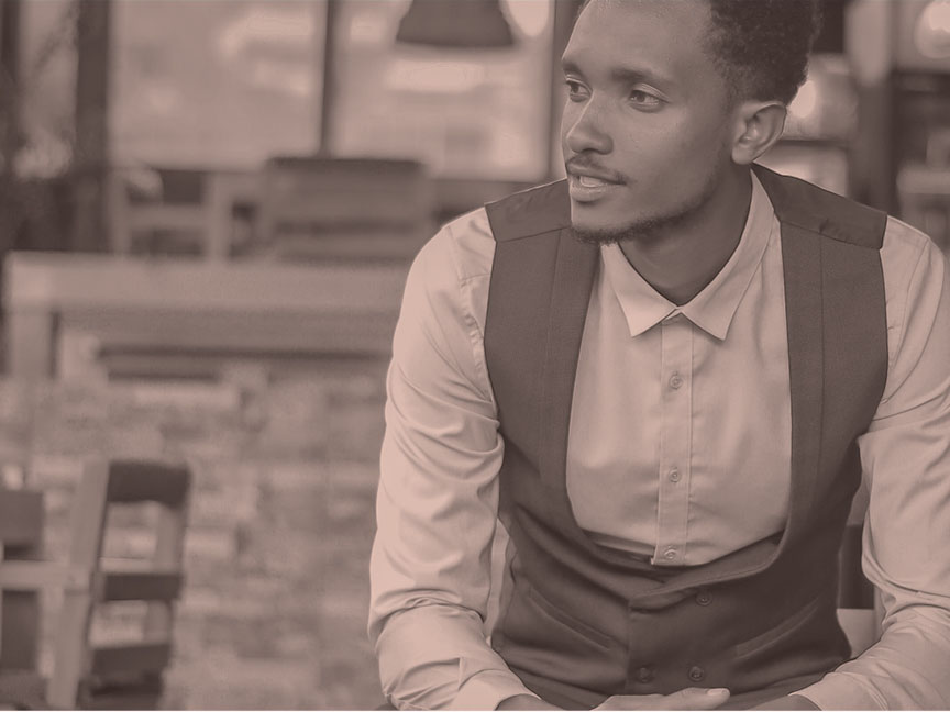 sepia-toned photo of young Ethiopian man in button-down shirt with vest 