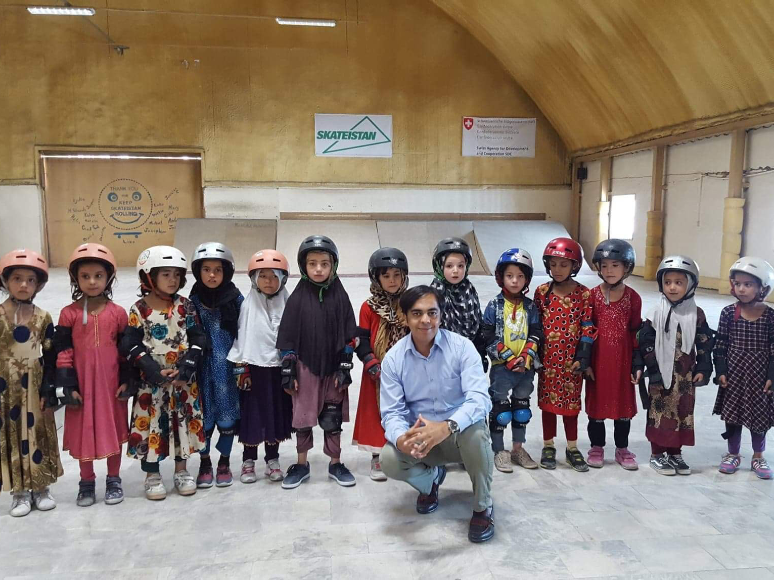 Soroush Kazemi with young girls in helmets and elbow pads at Skateistan