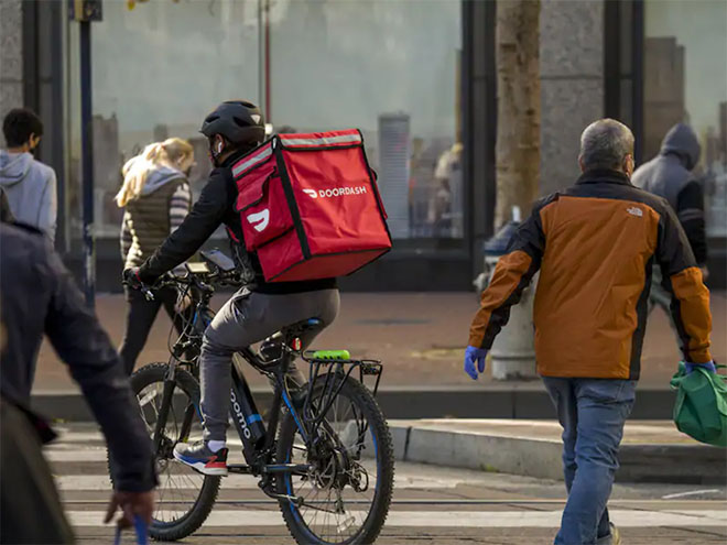 A DoorDash delivery person on a bike on the street