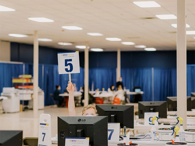 A nurse holds up a number 5 sign for her next vaccine recipient in a former department store in Morgantown, West Virginia