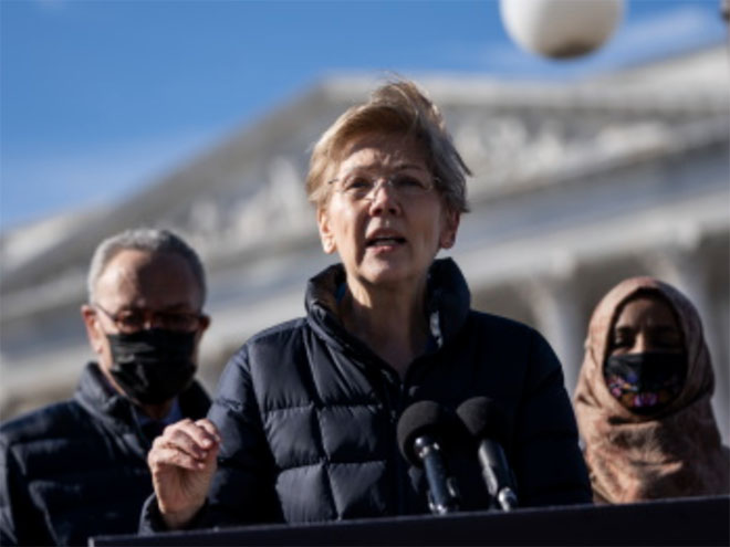Elizabeth Warren with Chuck Schumer and Ilhan Omar in the background, wearing face masks