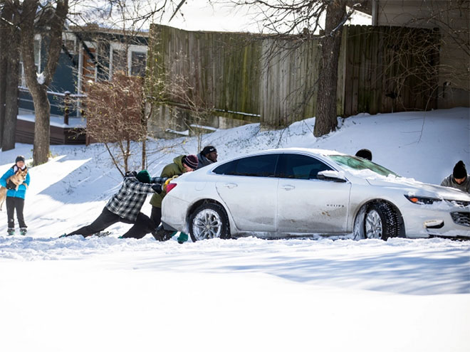 People pushing a car in the snow