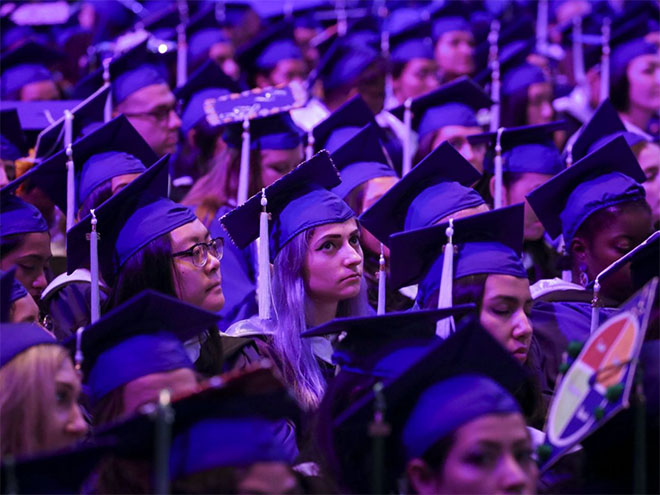 A sea of college graduates wearing caps and gowns