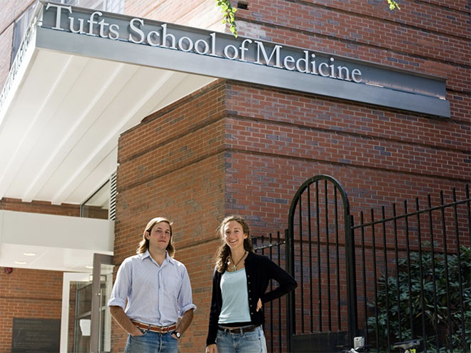 Two students standing under a Tufts School of Medicine sign