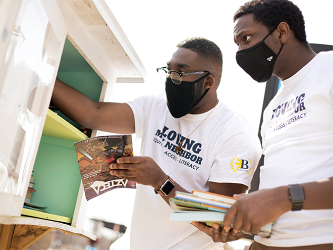 Isaac Cudjoe and Kevin Isabelle-Peete adding books to a Little Free Library