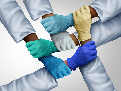multiple hands wearing medical gloves holding each others' wrists