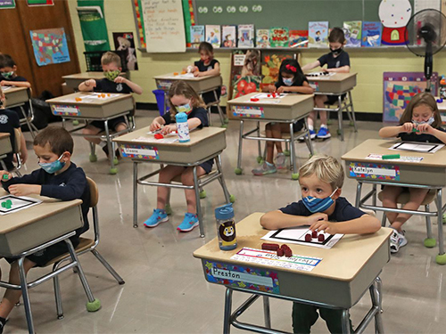 elementary students wearing masks sitting in a classroom