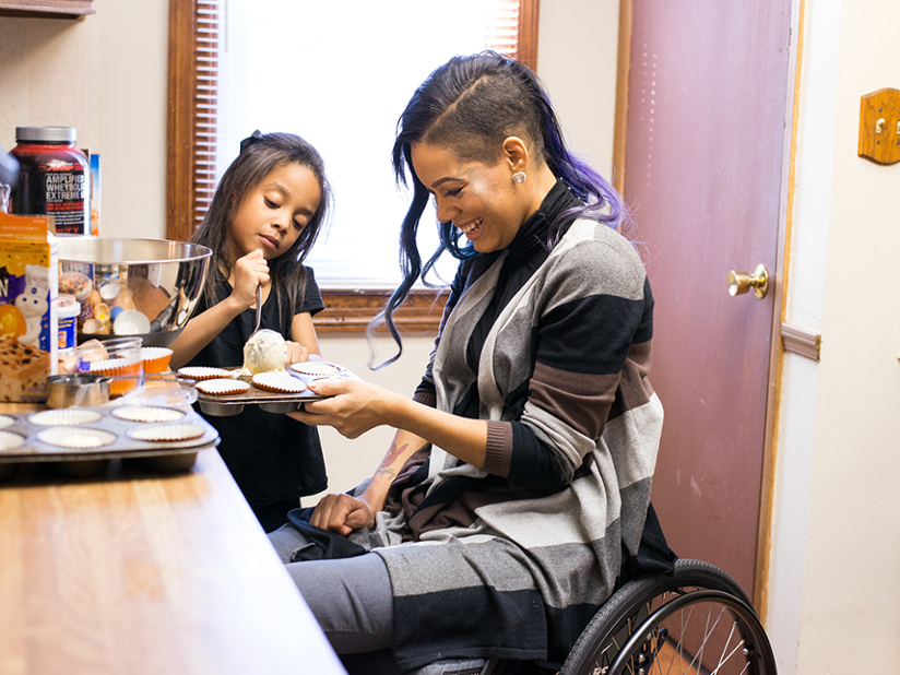 A woman in a wheelchair bakes cupcakes with a girl