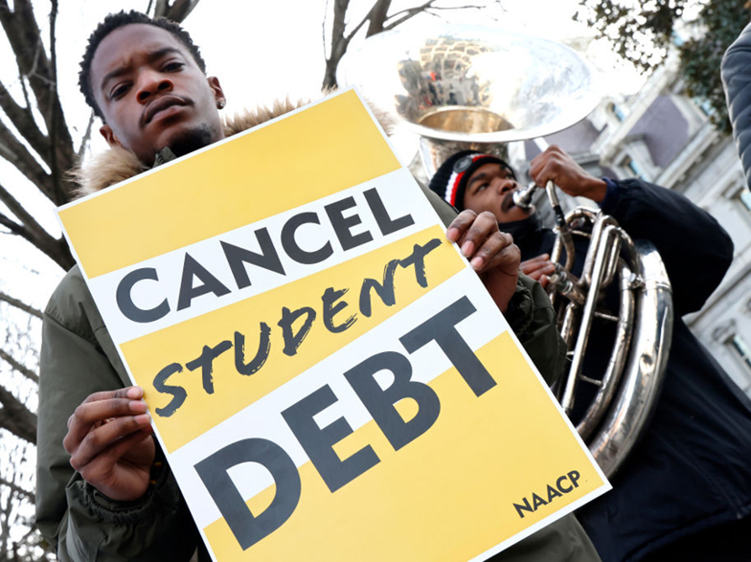 A man holds a sign that says "Cancel Student Debt"