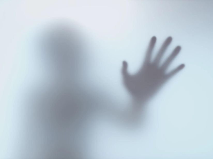 A silhouette of a person with their hand reaching towards the screen