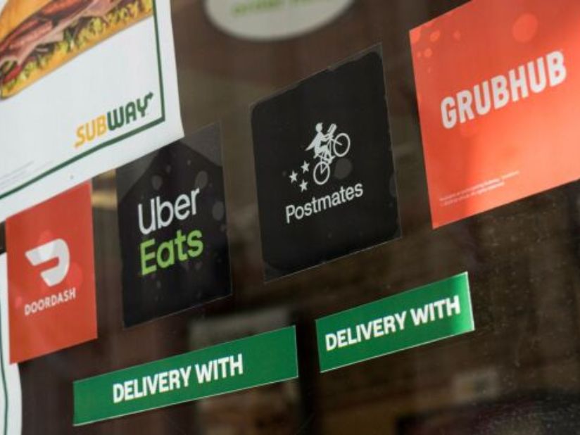 DoorDash Inc., Uber Eats, Postmates Inc., and GrubHub Inc. signage in the window of a Subway Restaurant in San Francisco. Some restaurant delivery services use independent contractors