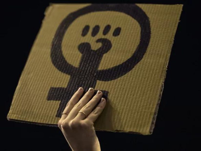 A hand holding the feminism symbol