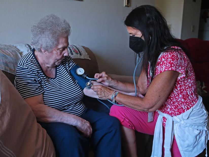 A woman taking an older person's blood pressure