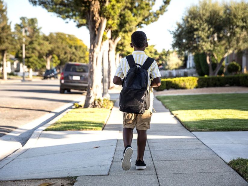 A black child walking through a neighborhood