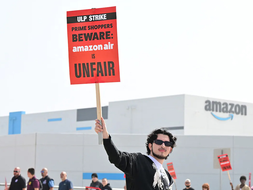 A man holds up a sign that says "ULP Strike: Prime Shoppers Beware, Amazon Air is Unfair"