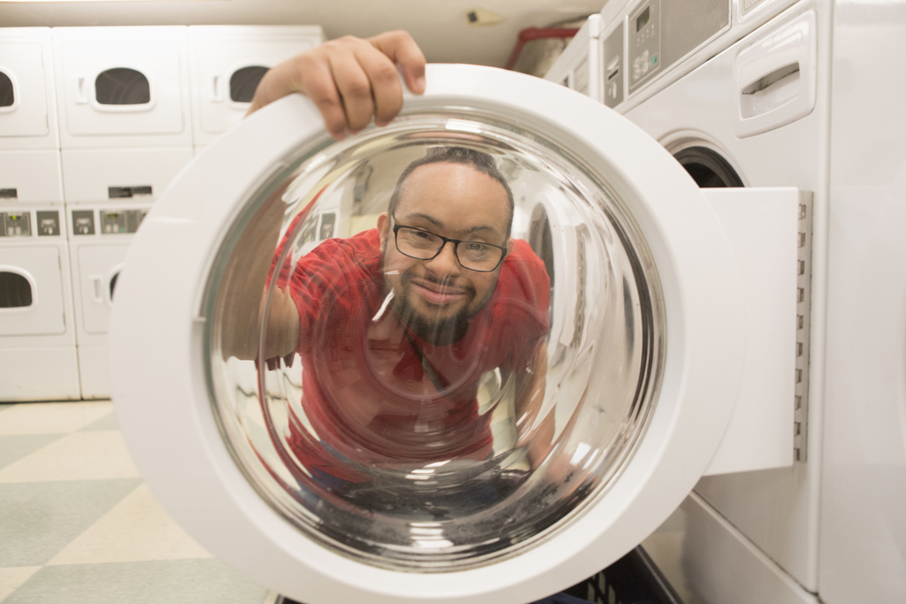 A man peers through the glass door on a drying machine.