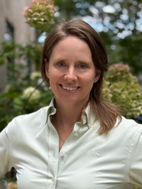 Headshot of Sarah E. Whiting smiling, with a flowering hydrangea bush in the background