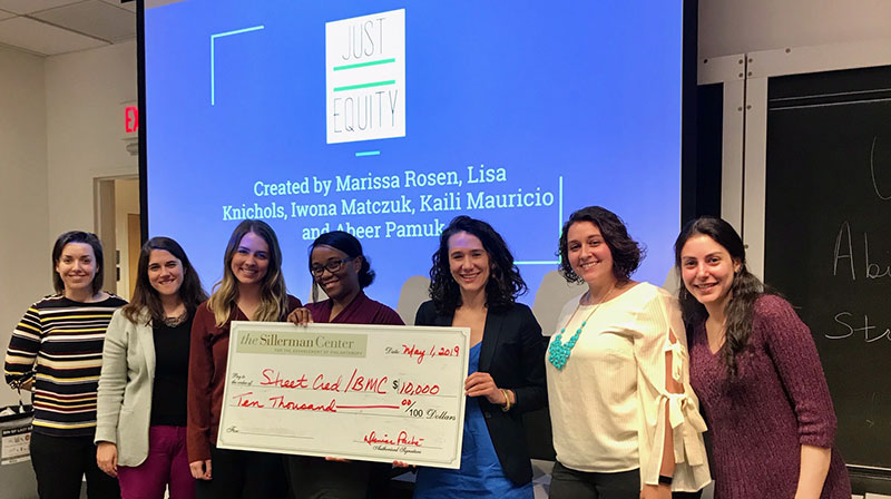 Participants in 2019 Graduate Philanthropy Course, holding check made out to "Street Cred/BMC"