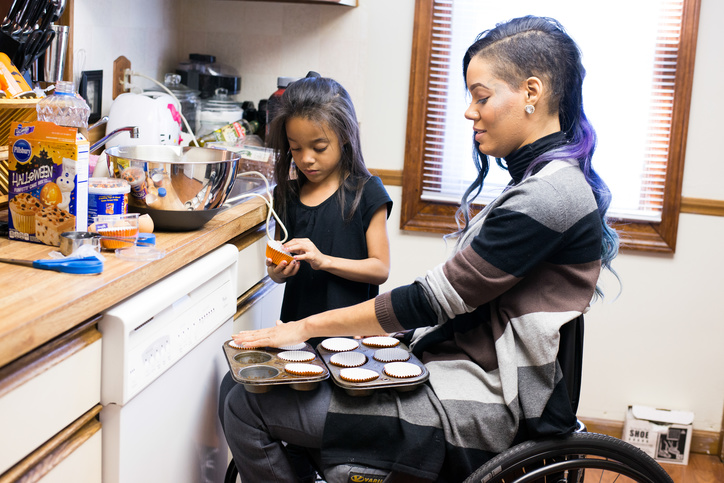 Una madre en silla de ruedas y su hija pequeña preparan magdalenas para hornear