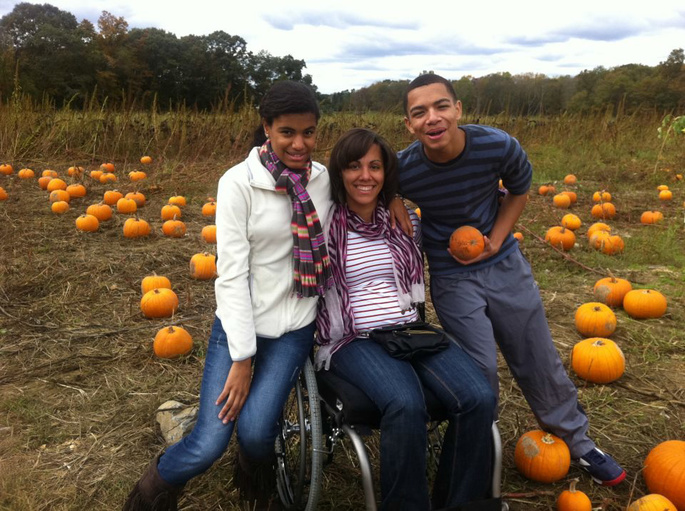A mother using a wheelchair with her teenage children in a pumpkin patch