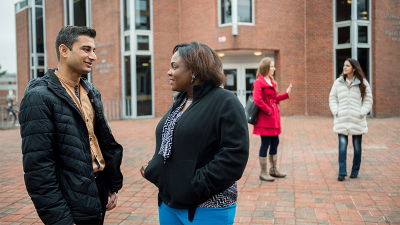 students chatting in front of library wearing winter coats