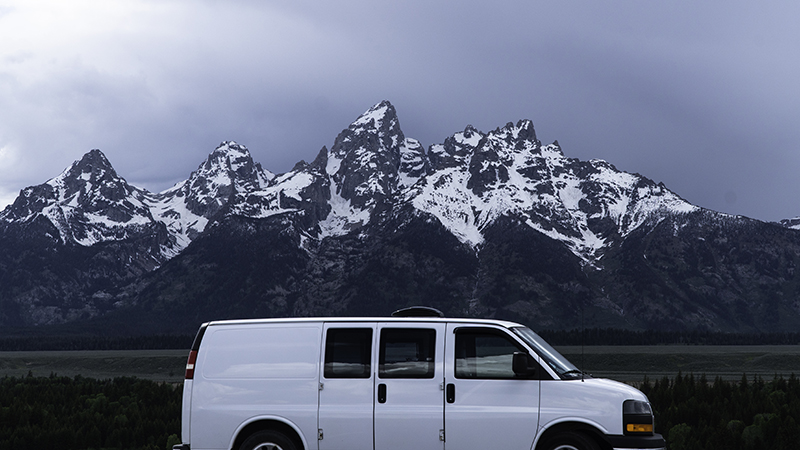 A white van in front of snow-covered mountains